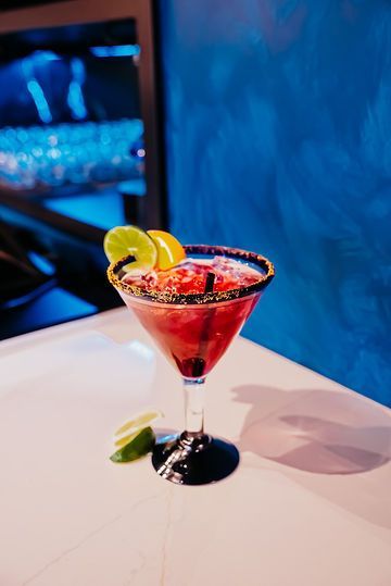 A martini with strawberries and limes on a table
