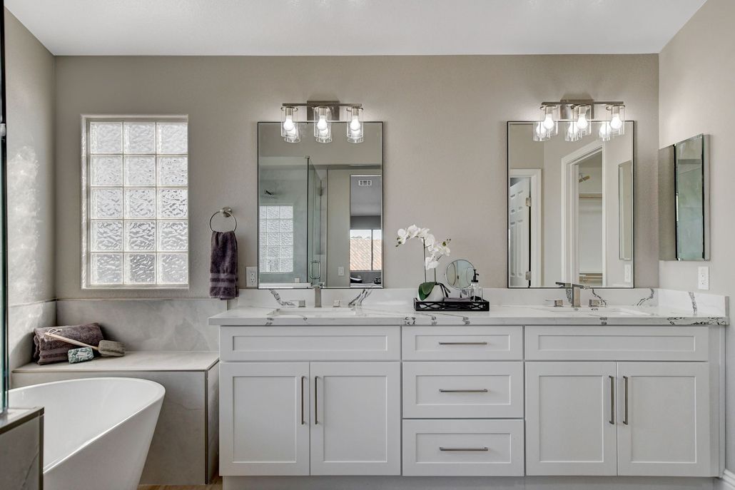 Bright white bathroom with double vanity, two mirrors, and a window.
