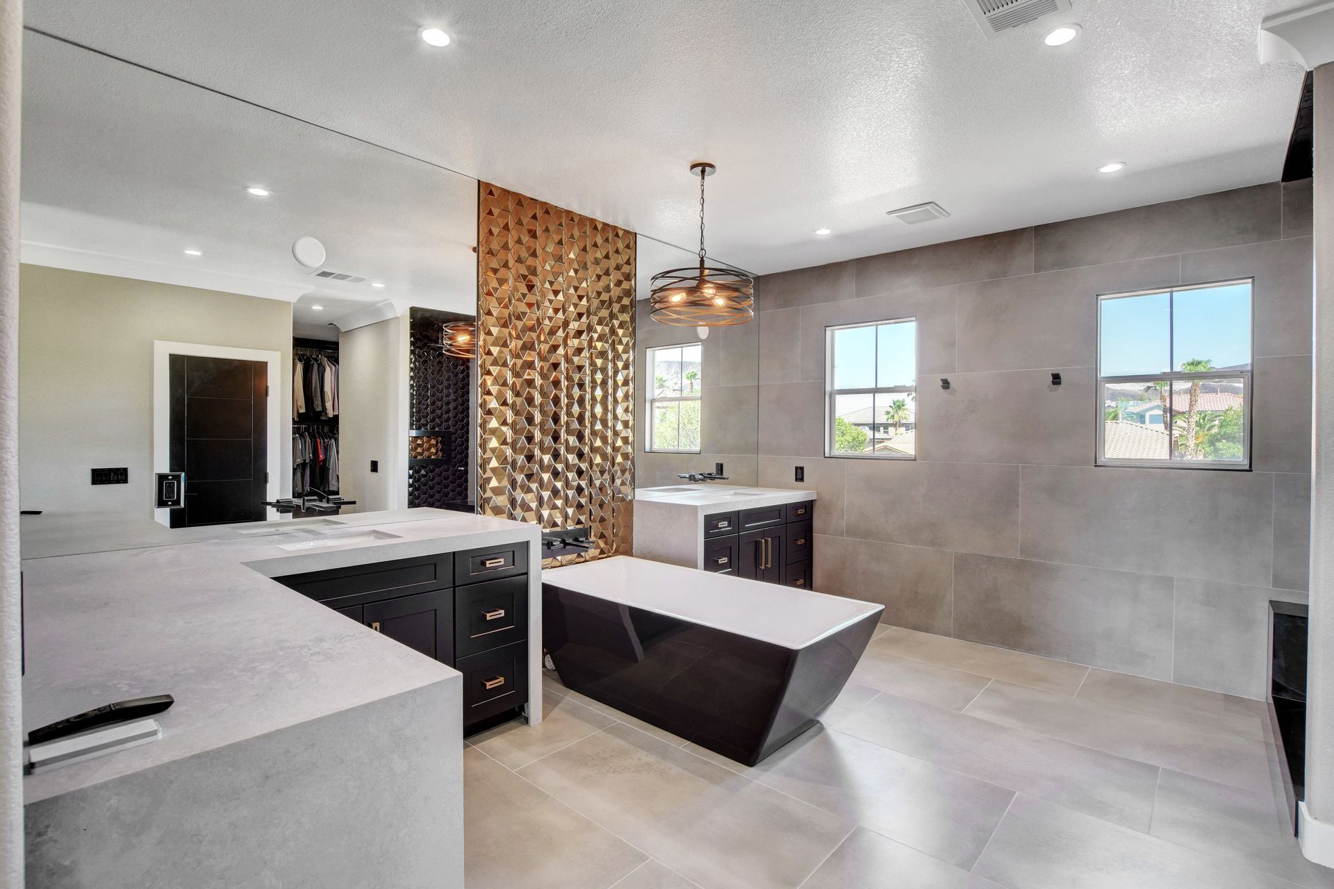Modern bathroom with gray walls, black cabinets, a gold screen, and a freestanding tub.