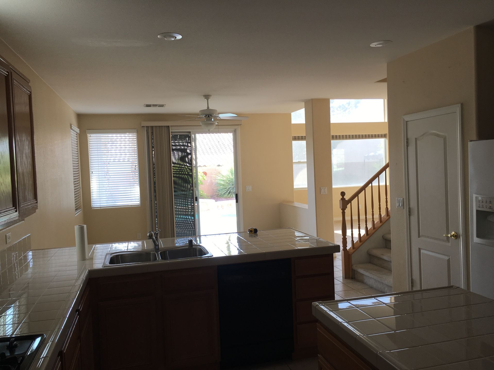 Kitchen interior with granite countertops, wooden cabinets, and a doorway leading outside.