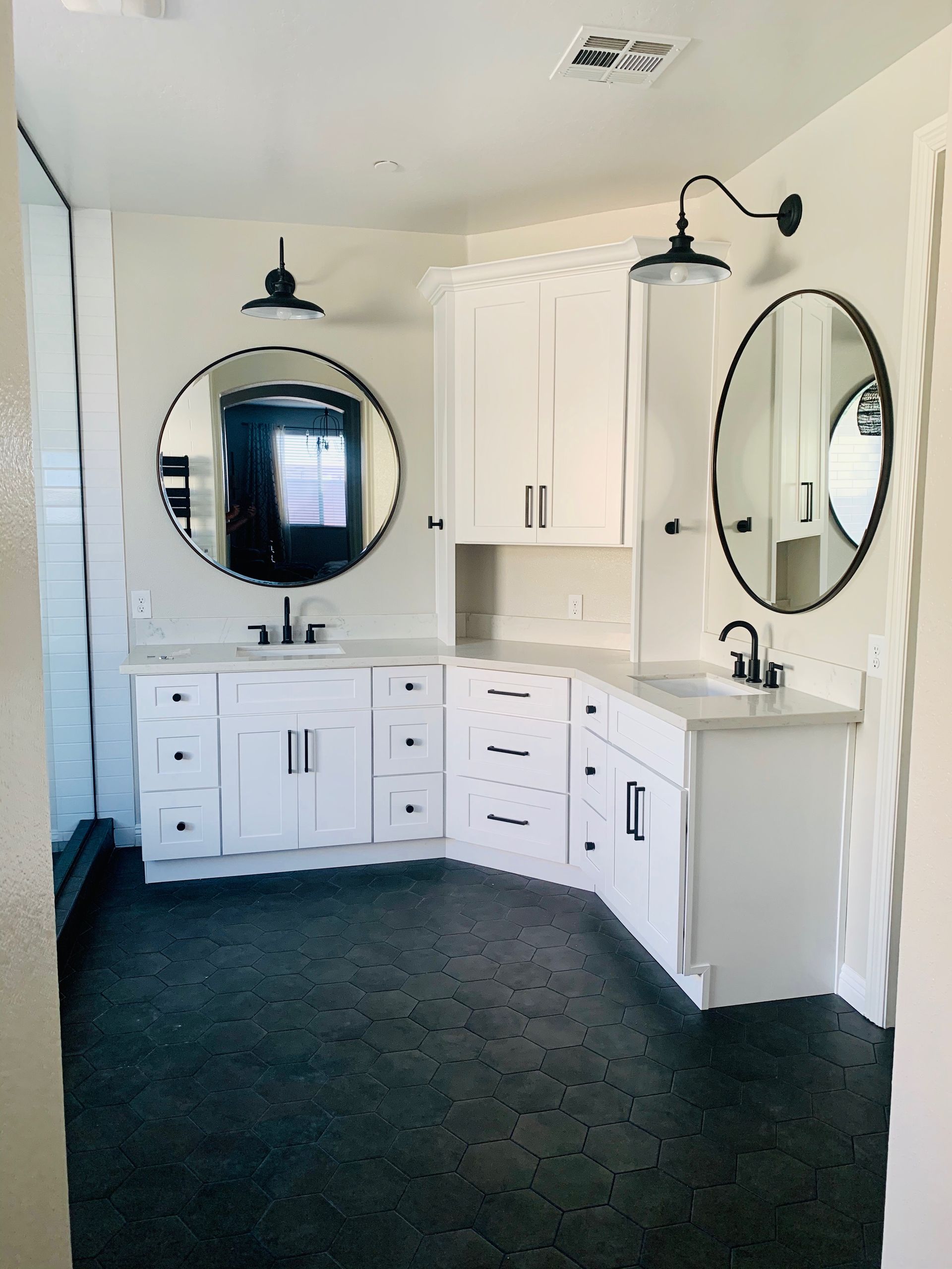 Bathroom with white cabinets, dark countertops, and black fixtures.