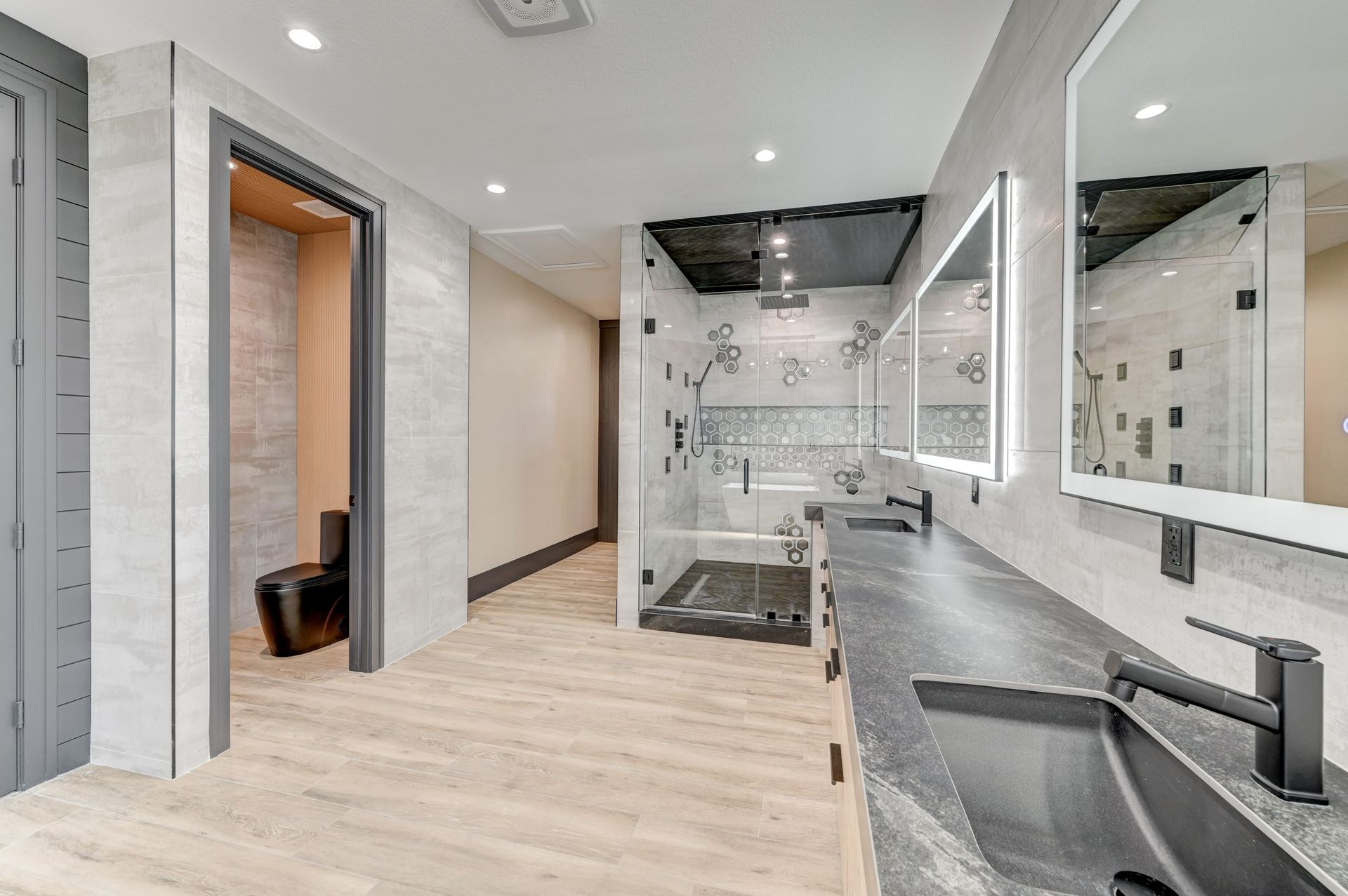 Spacious modern bathroom with a double vanity, large shower, and a separate doorway to a seating area.