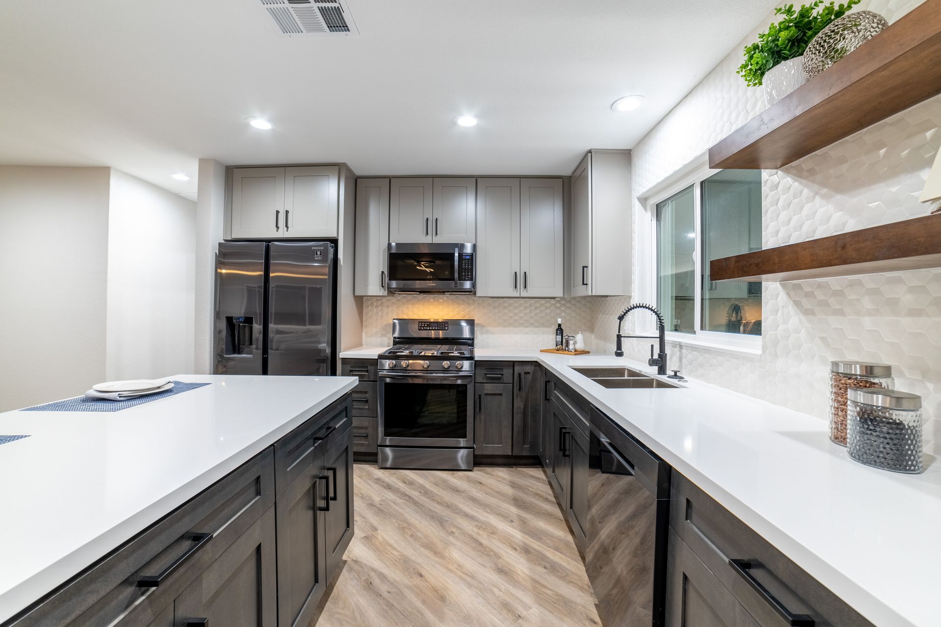 Modern kitchen with gray cabinets, stainless steel appliances, and white countertops.