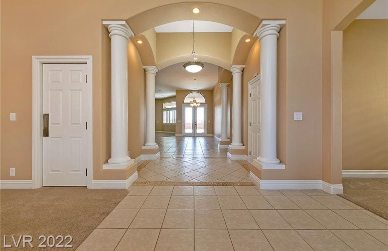 Grand foyer with columns, arches, and tile flooring.
