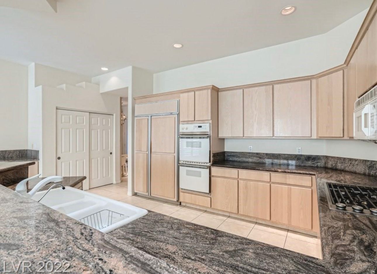Kitchen with light wood cabinets, granite countertops, and built-in appliances.
