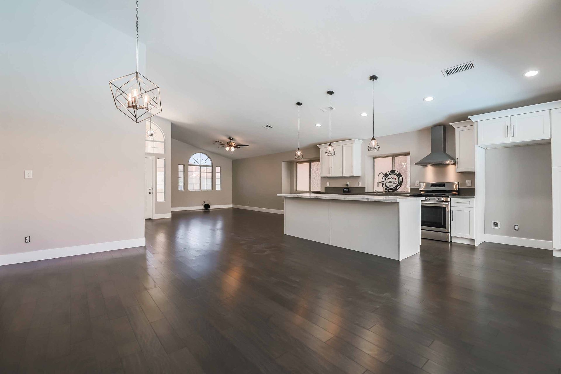 Spacious open-concept kitchen and living area with dark wood floors, white cabinets, and a kitchen island.