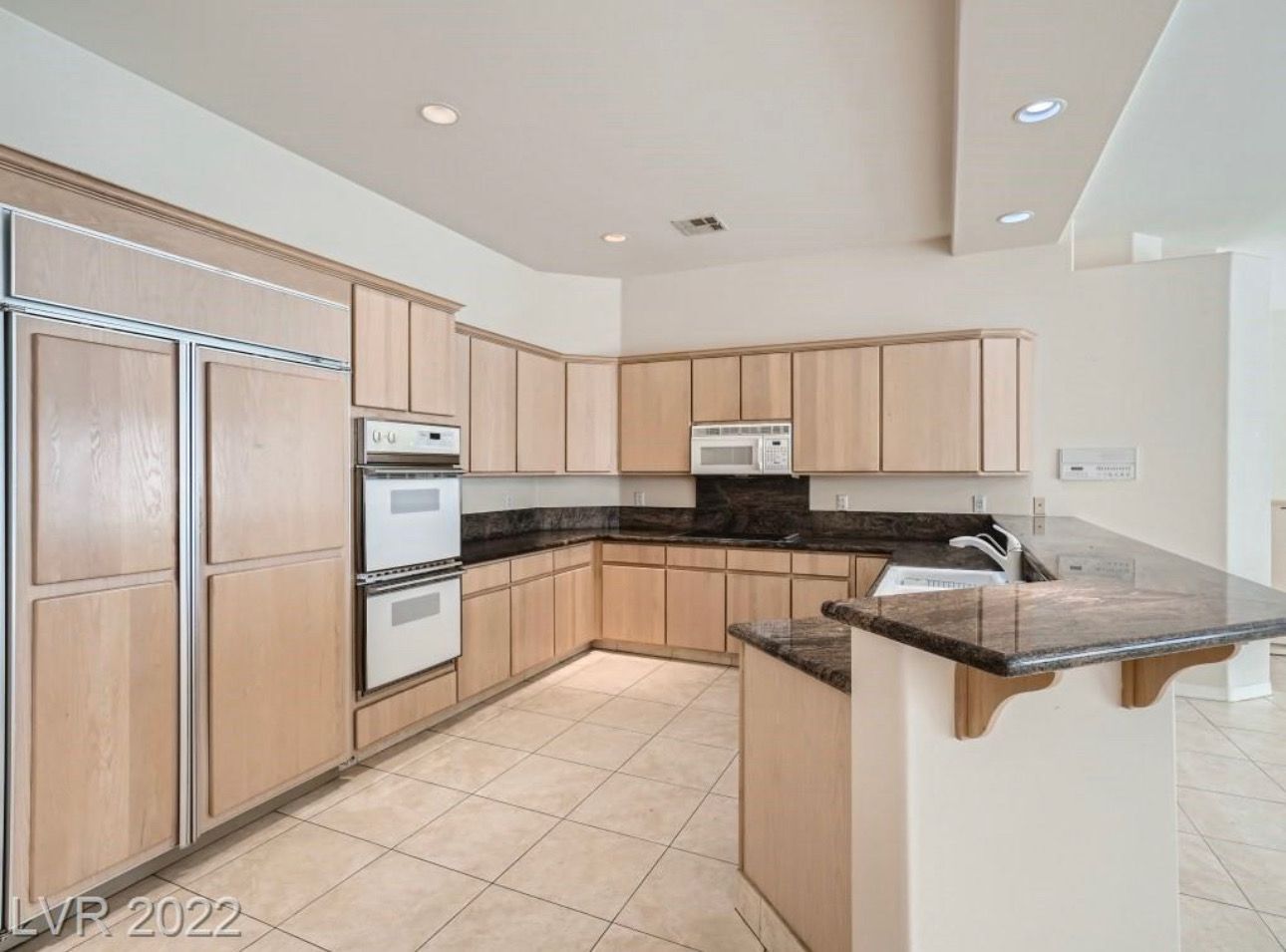 Kitchen with light wood cabinets, granite countertops, and stainless steel appliances.