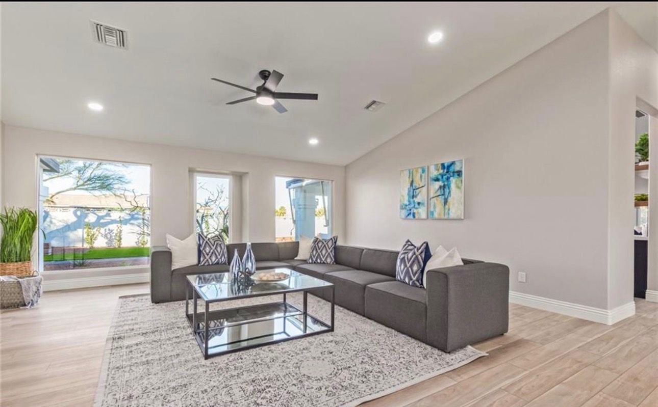 Modern living room with gray sectional sofa, rug, and coffee table; blue artwork on wall.