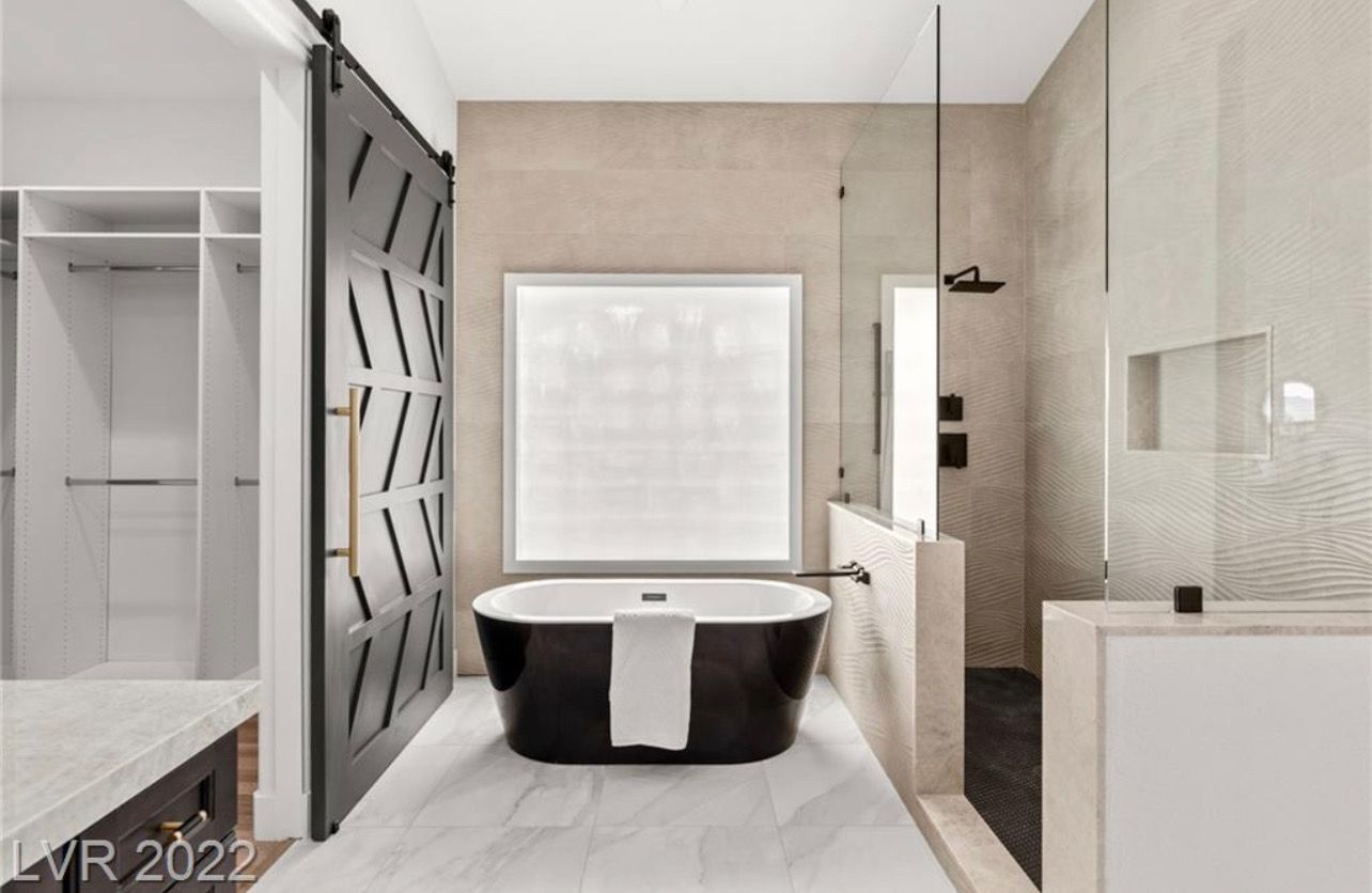 Bathroom with black tub, white walls, walk-in shower, and sliding black door.