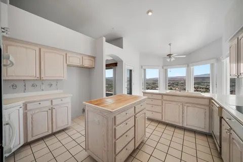 Kitchen with cream cabinets, island, tile floor, and large windows with a view.