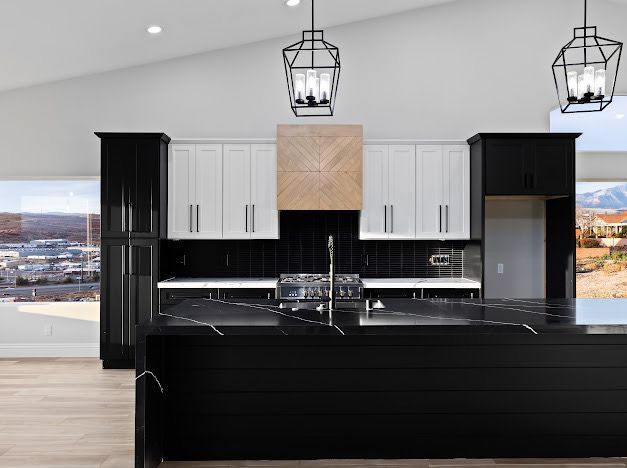 Modern kitchen with black and white cabinets, black countertops, and a stone range hood.