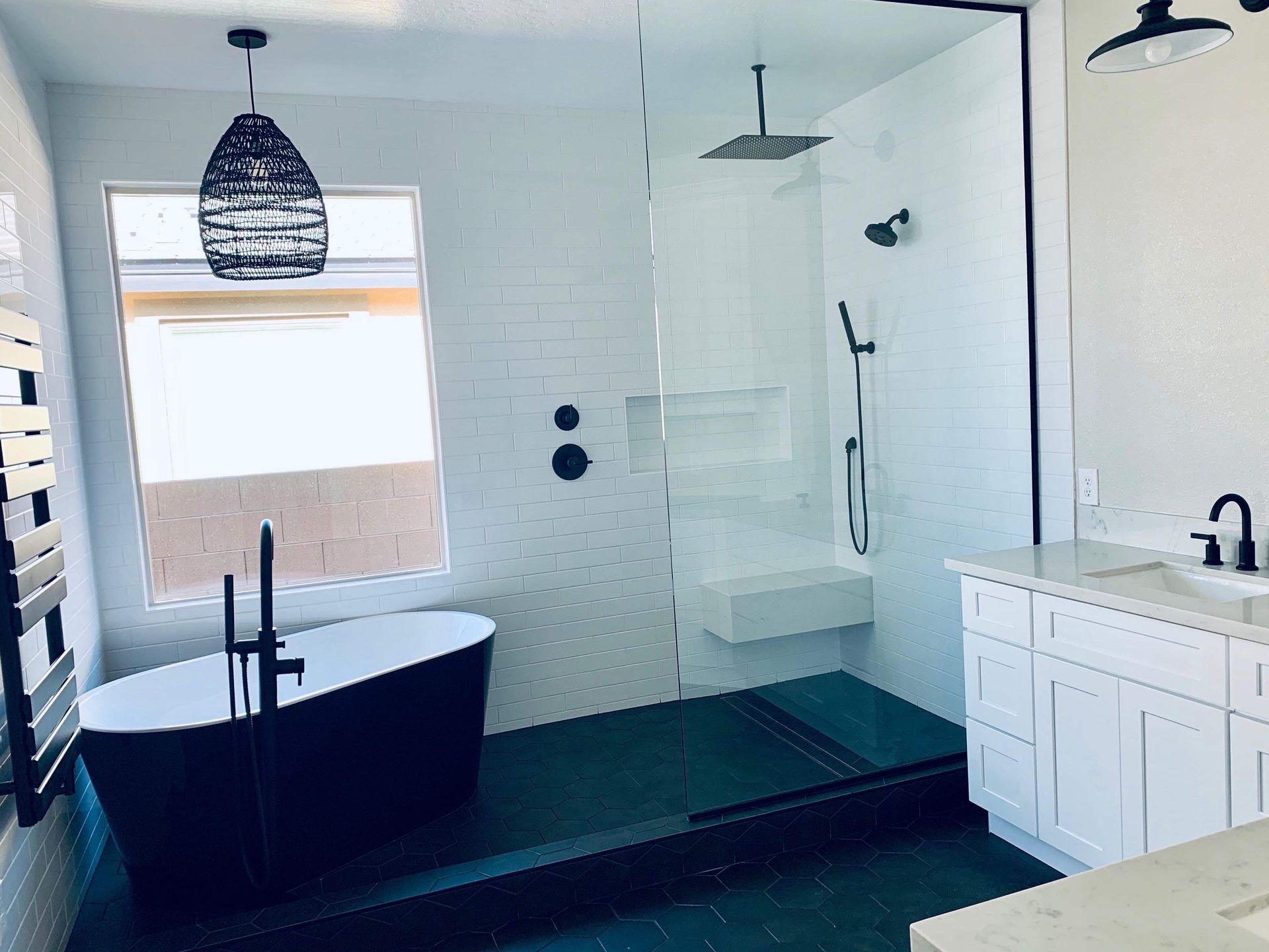 Modern bathroom with black soaking tub, large shower, white cabinets, and black fixtures.