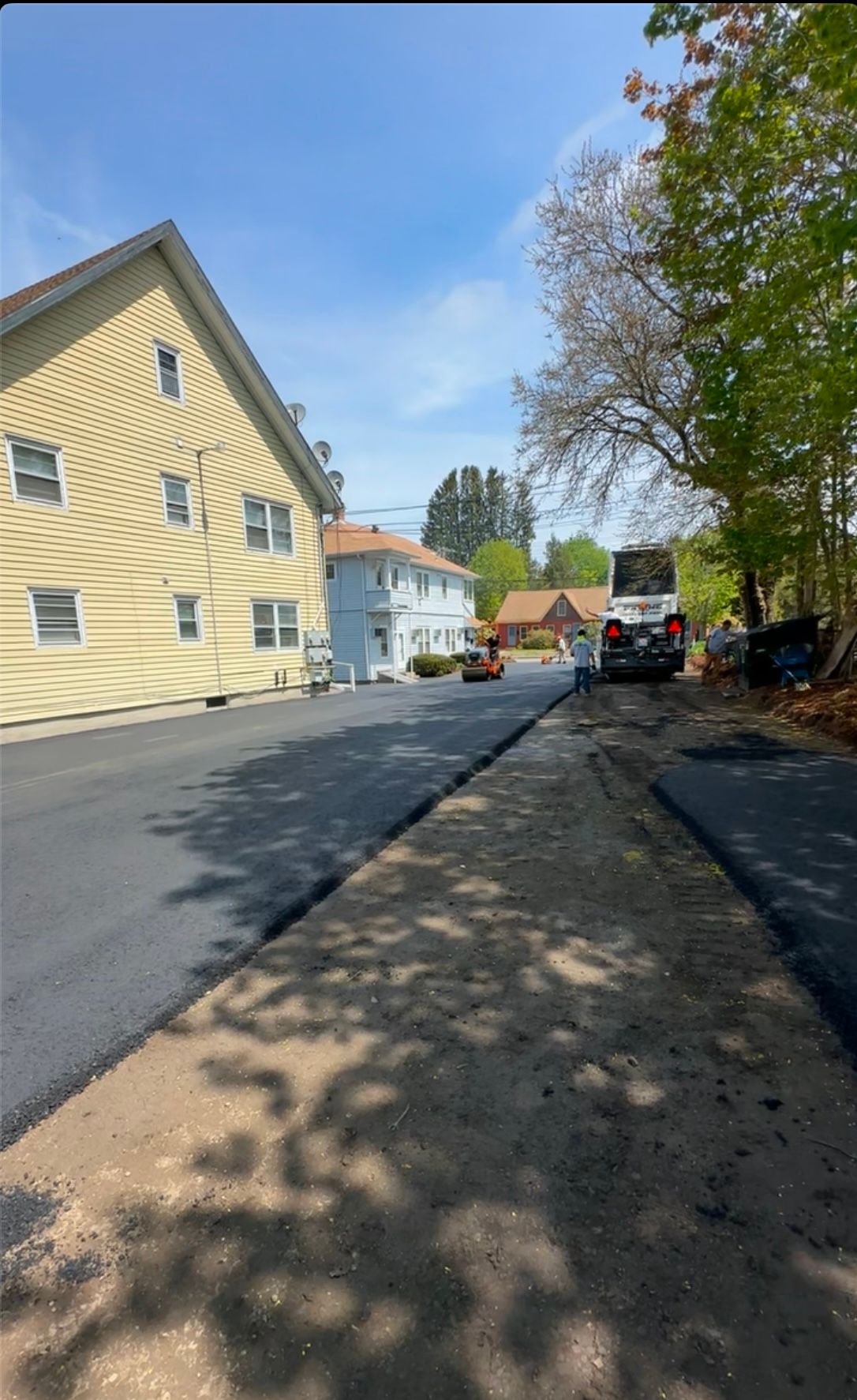 A car is parked on the side of a road next to a house.