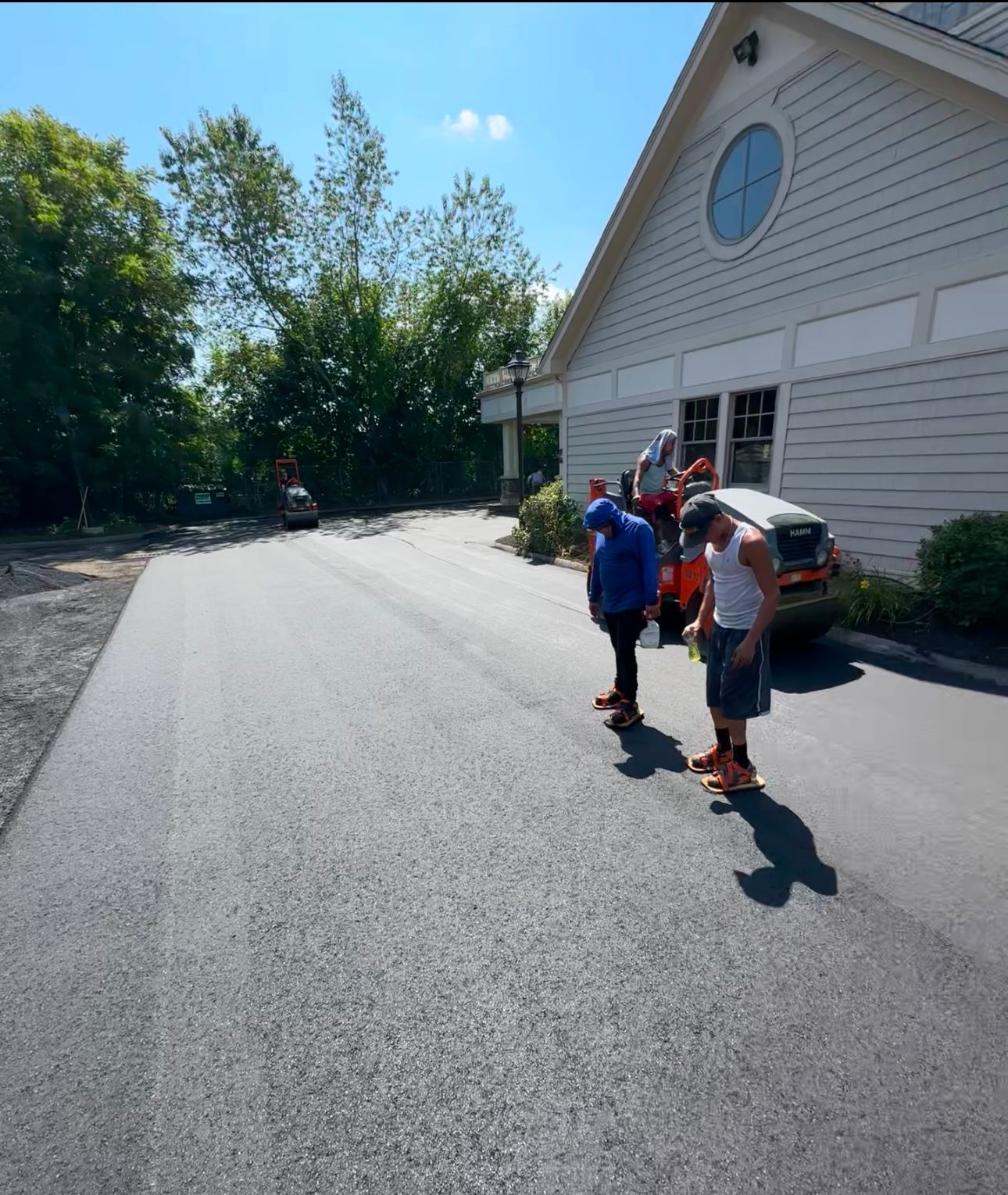 A group of people standing on a road in front of a building