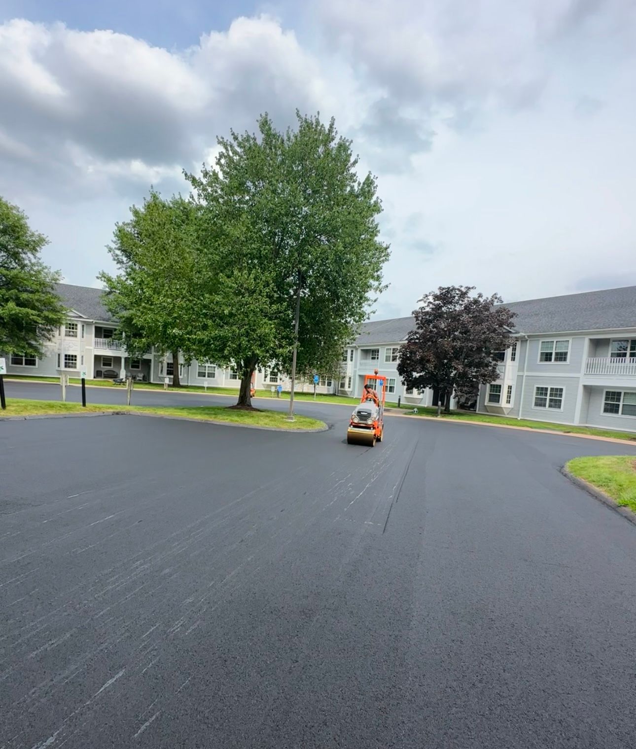 A paver is driving down a road in front of a building
