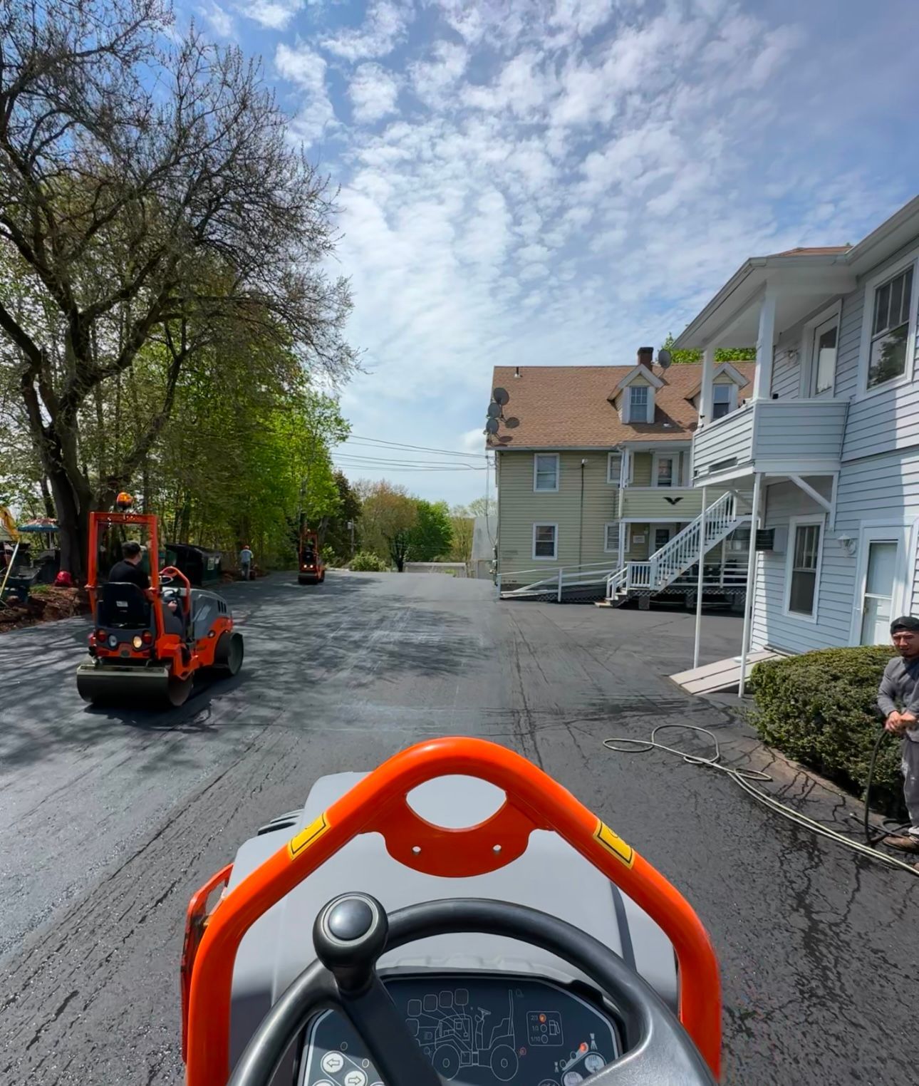 A person is driving a paver in front of a house