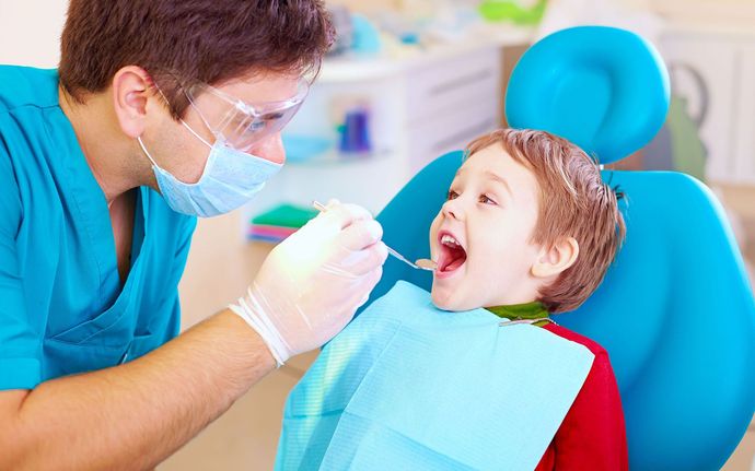 a young boy is sitting in a dental chair getting his teeth examined by a dentist