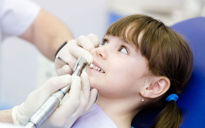 a little girl is getting her teeth examined by a dentist