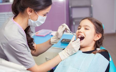 a young girl is getting her teeth examined by a dentist