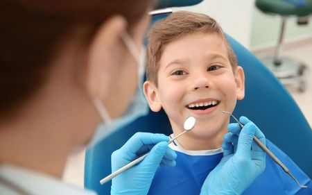 a young boy is sitting in a dental chair while a dentist examines his teeth
