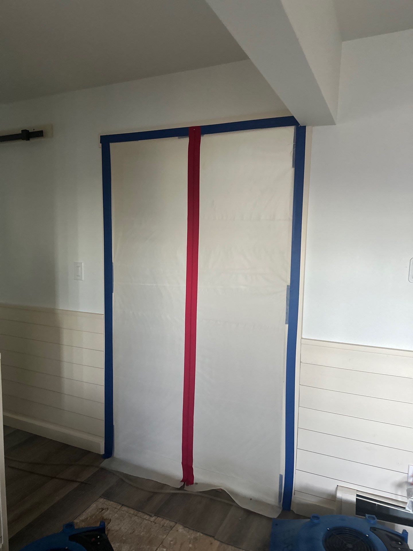A room with white walls and blue and red tape on the doors