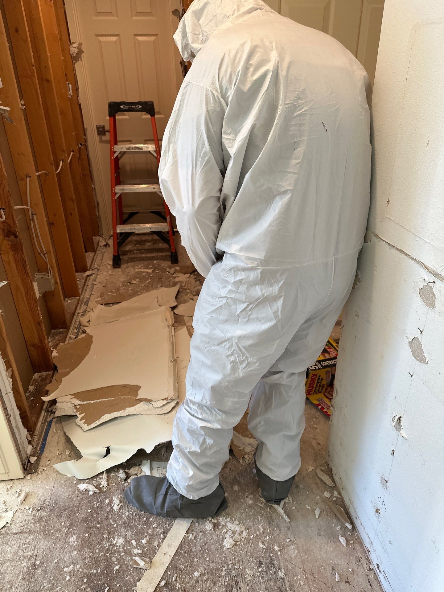 A man in a white suit is standing in a room