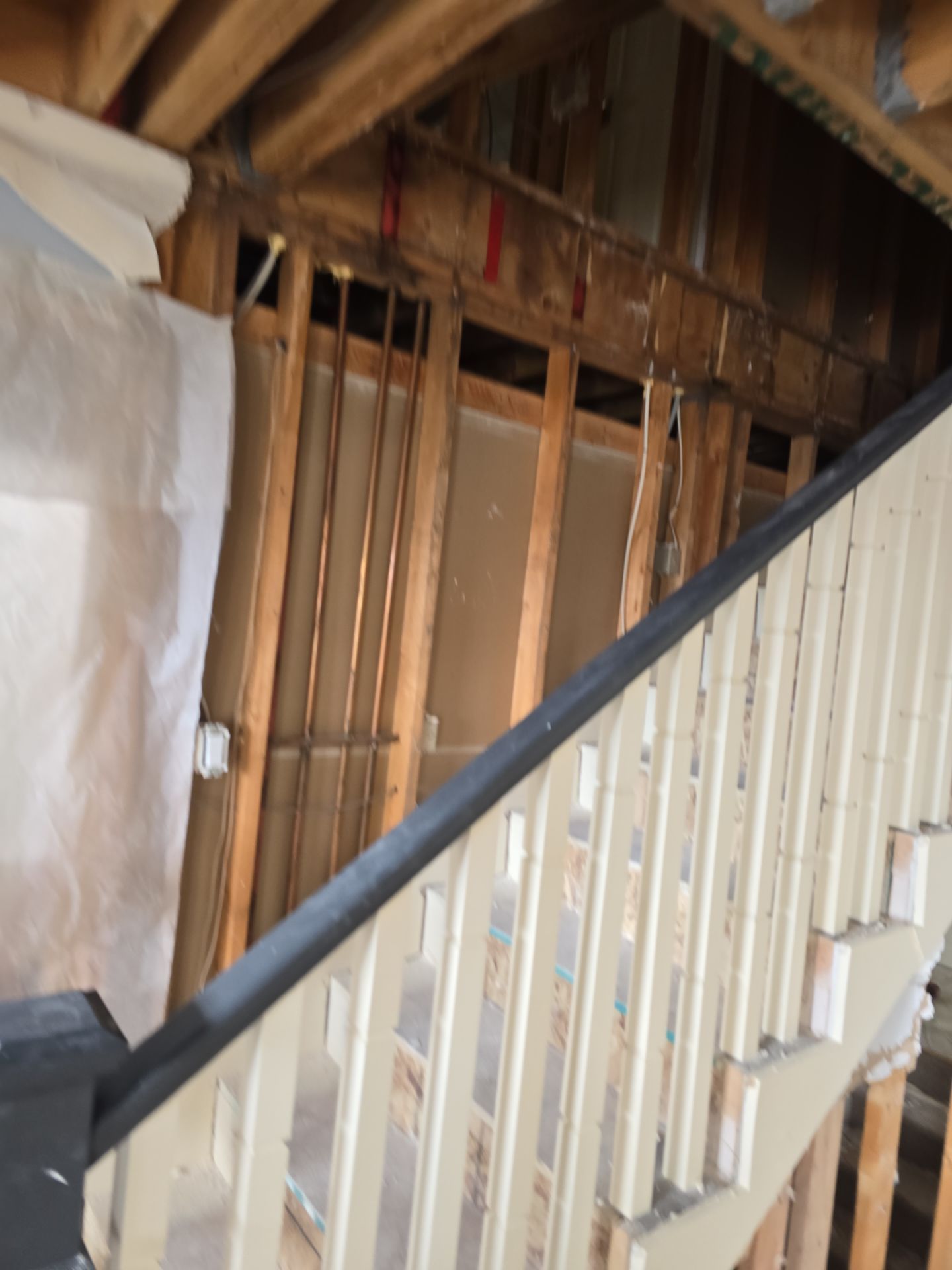 A wooden staircase with a black railing is under construction