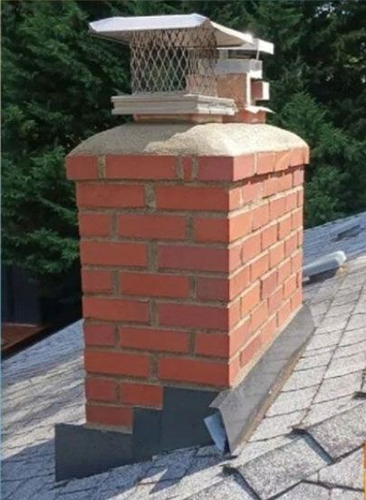 Red brick chimney with metal flashing and a chimney cap on a shingled roof.