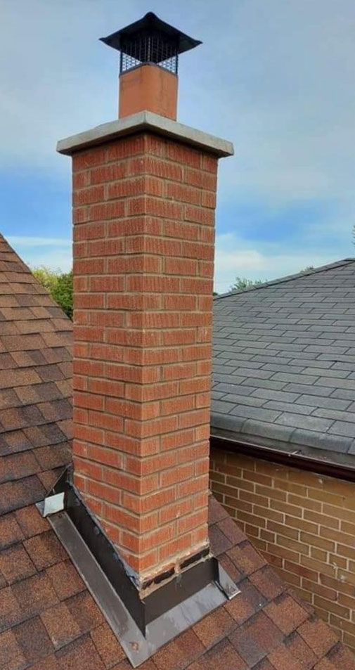 Brick chimney with a metal cap on a shingled roof.