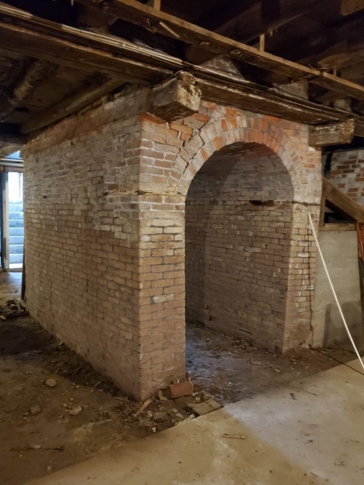 Brick structure with arched openings in a basement setting.