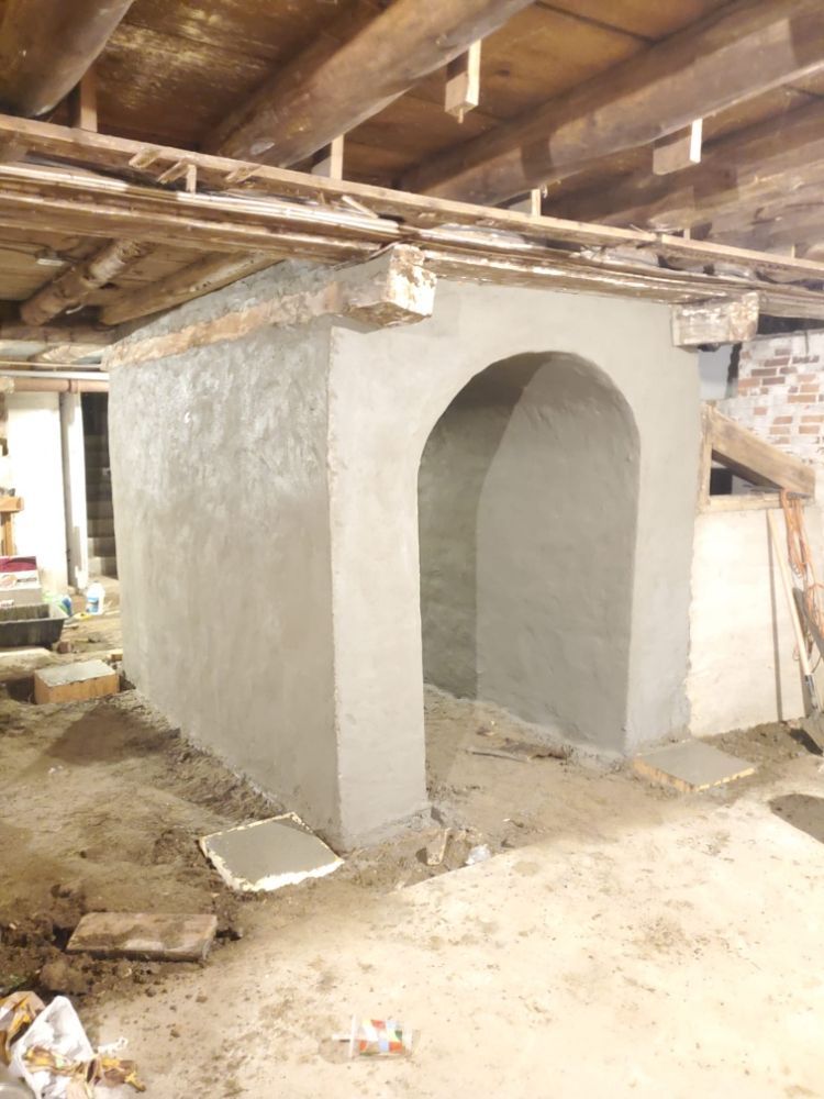 Gray concrete structure with arched doorway under wooden beams.
