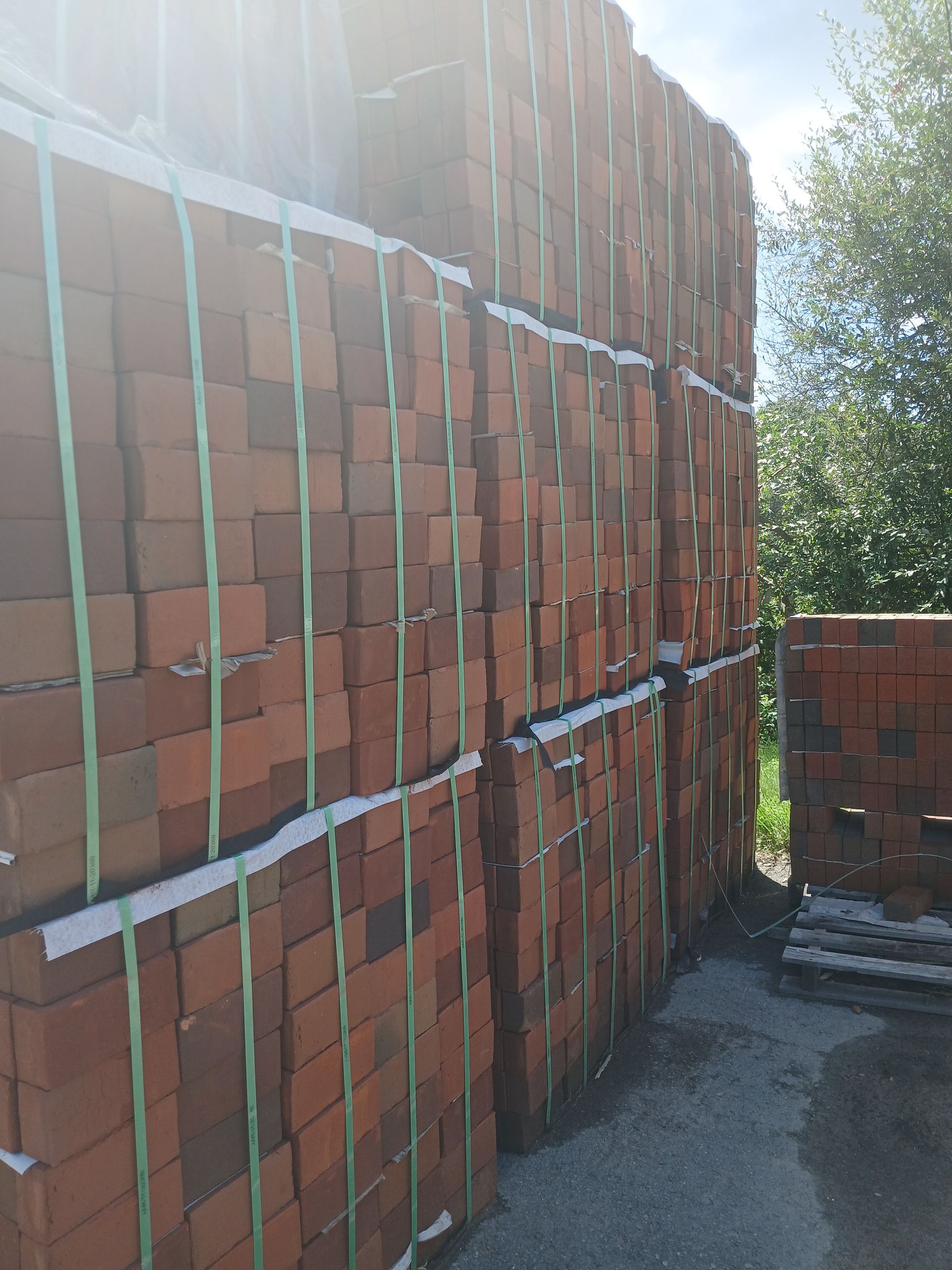 Stacks of red bricks bound together outdoors, ready for construction.