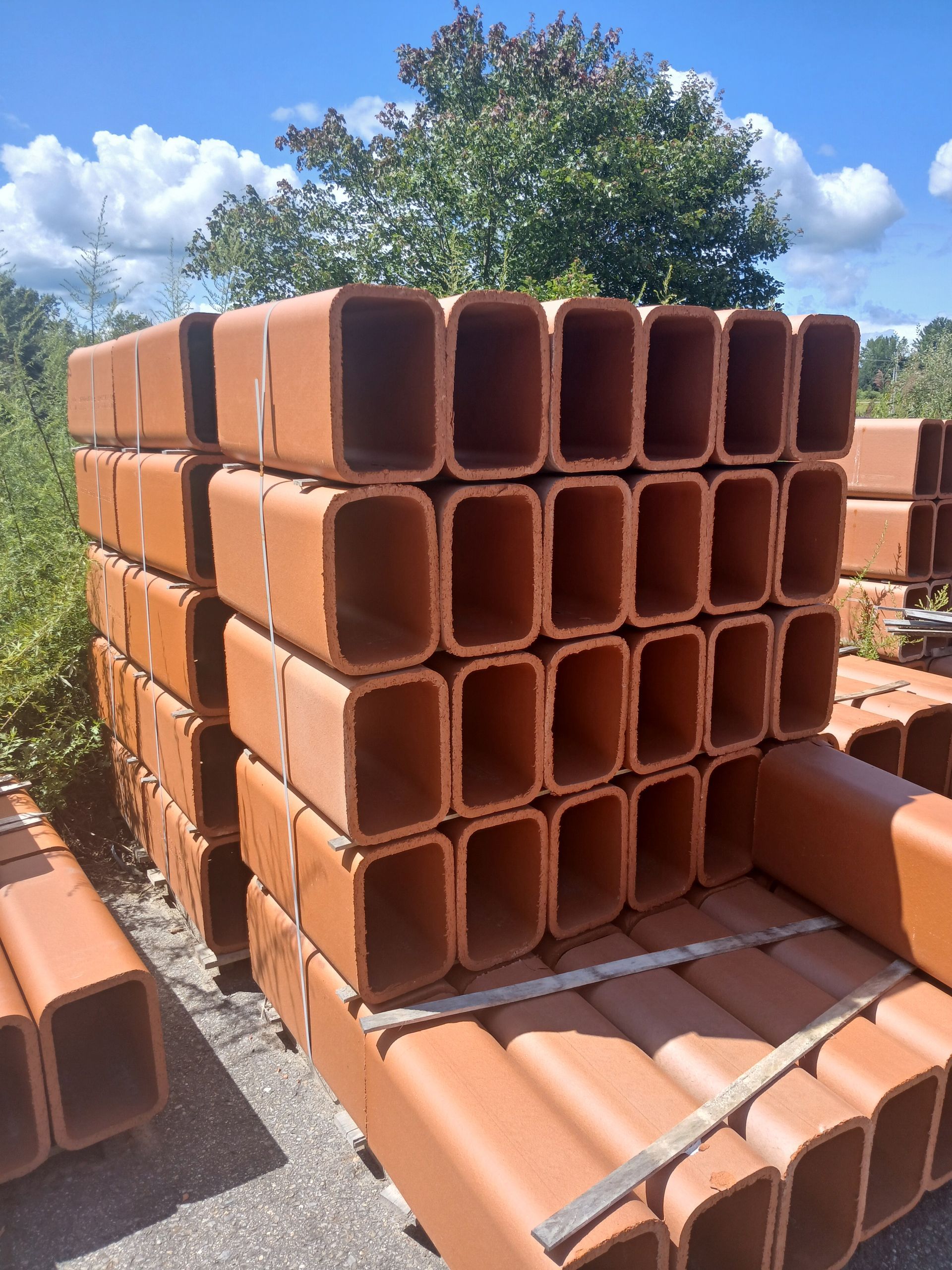 Stack of terracotta rectangular chimney flue sections outdoors.