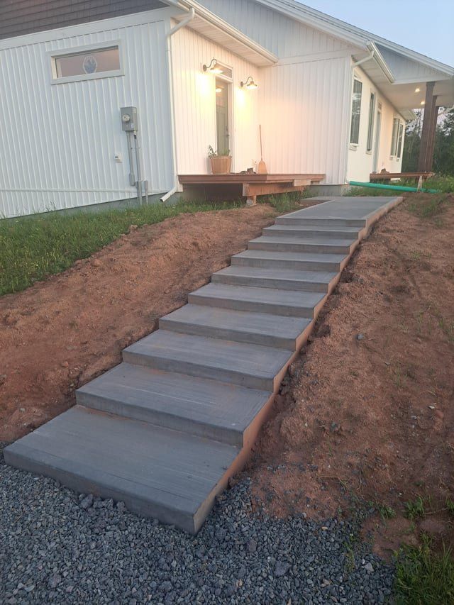 Gray concrete steps leading up a sloped dirt path to a white house with a small deck.