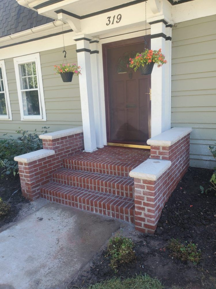 Brick steps lead up to a home's front door, with hanging flower baskets.