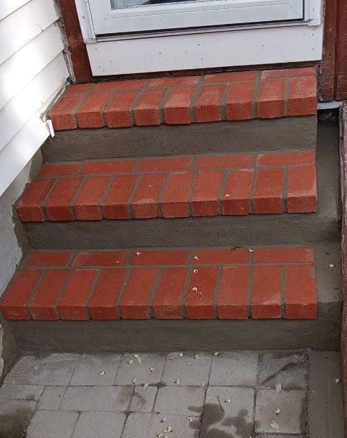 Brick steps leading up to a door. Red bricks on concrete.