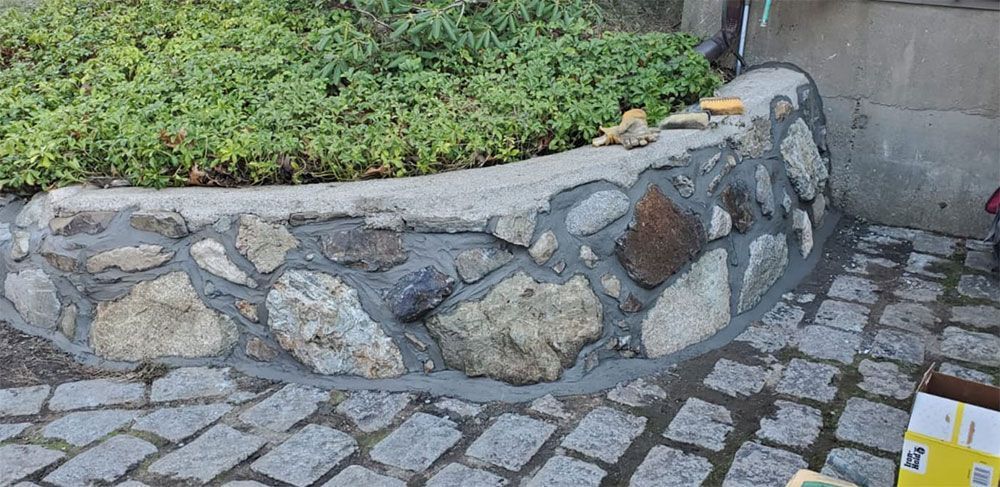 Stone foundation of a building with a white door, next to a paved surface.