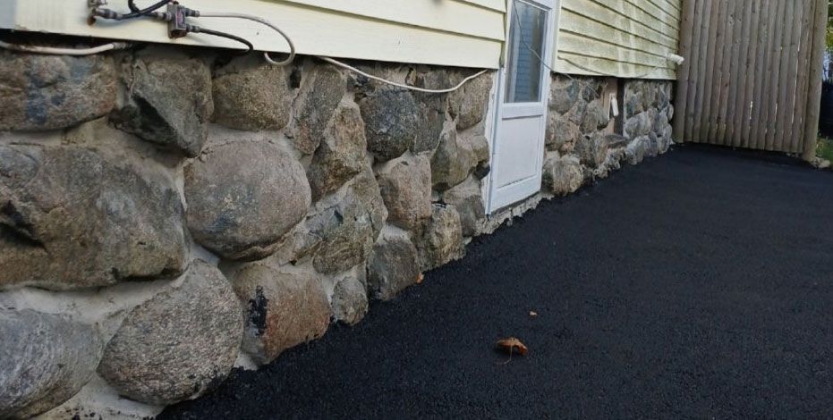 Stone foundation of a building with a white door, asphalt ground.