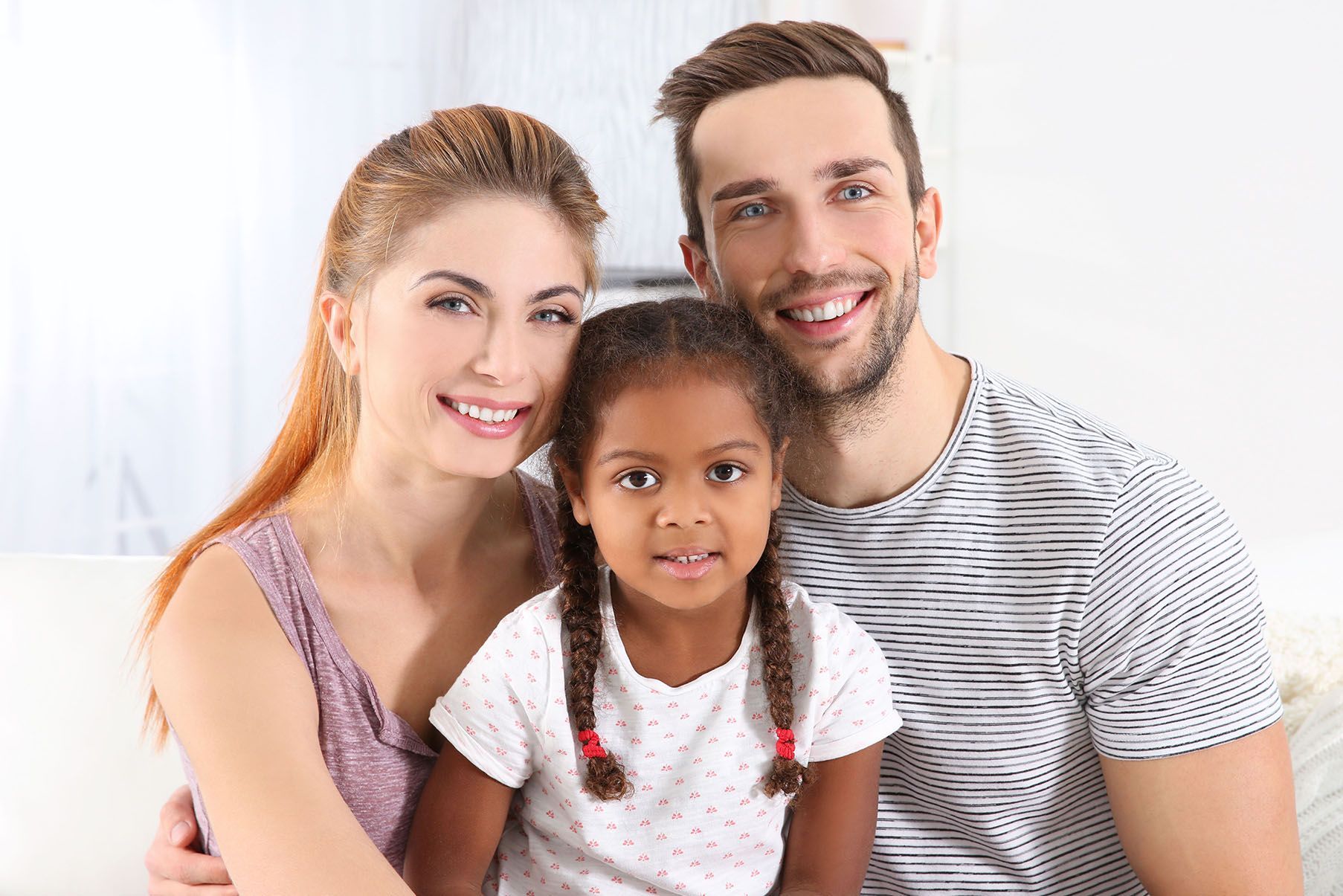 A family is posing for a picture while sitting on a couch.