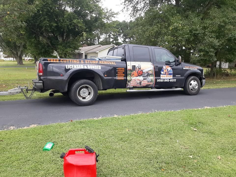 Black work truck with company graphics parked on asphalt next to green grass; gas can in foreground.