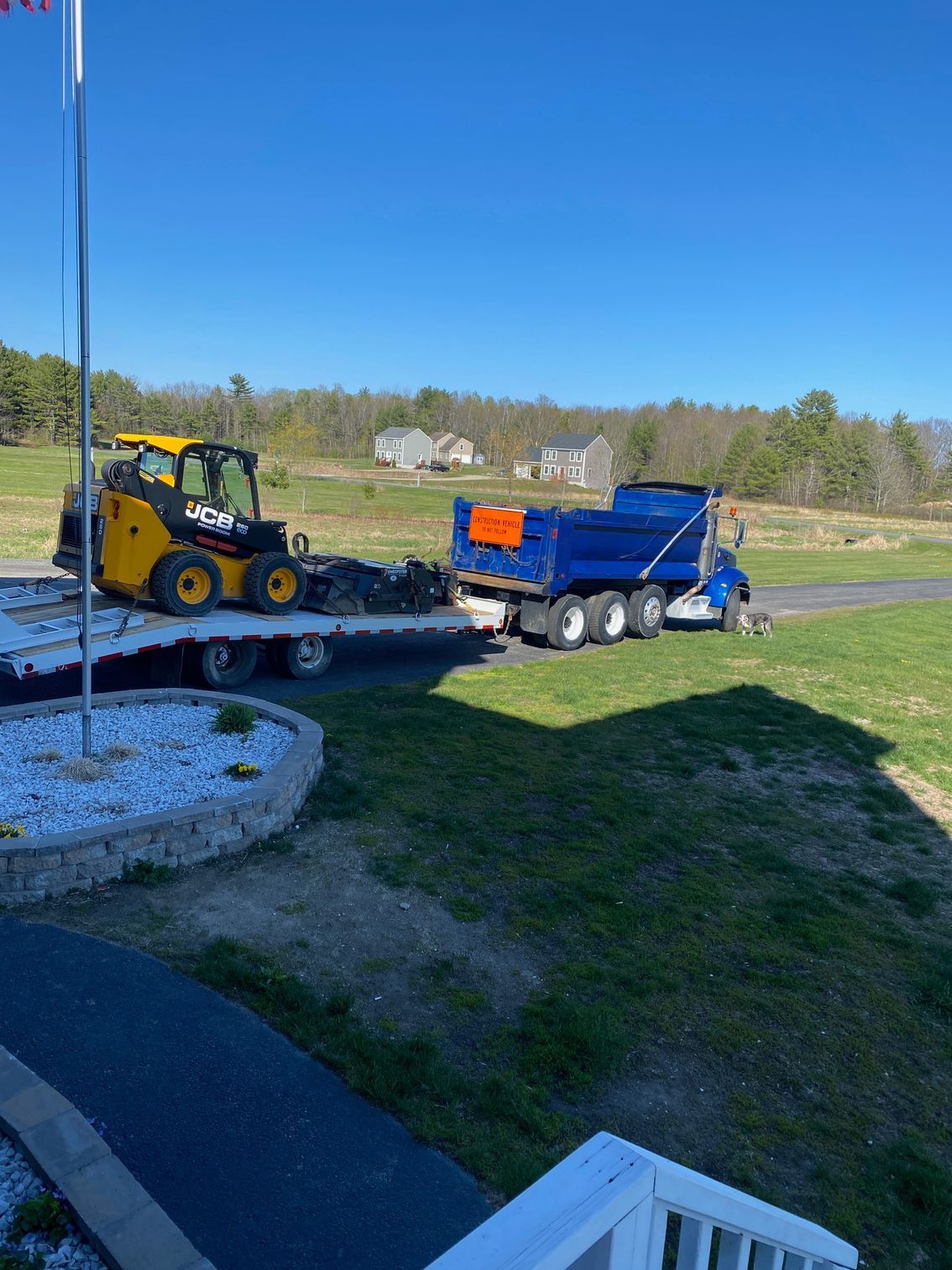 A bulldozer is being towed by a dump truck