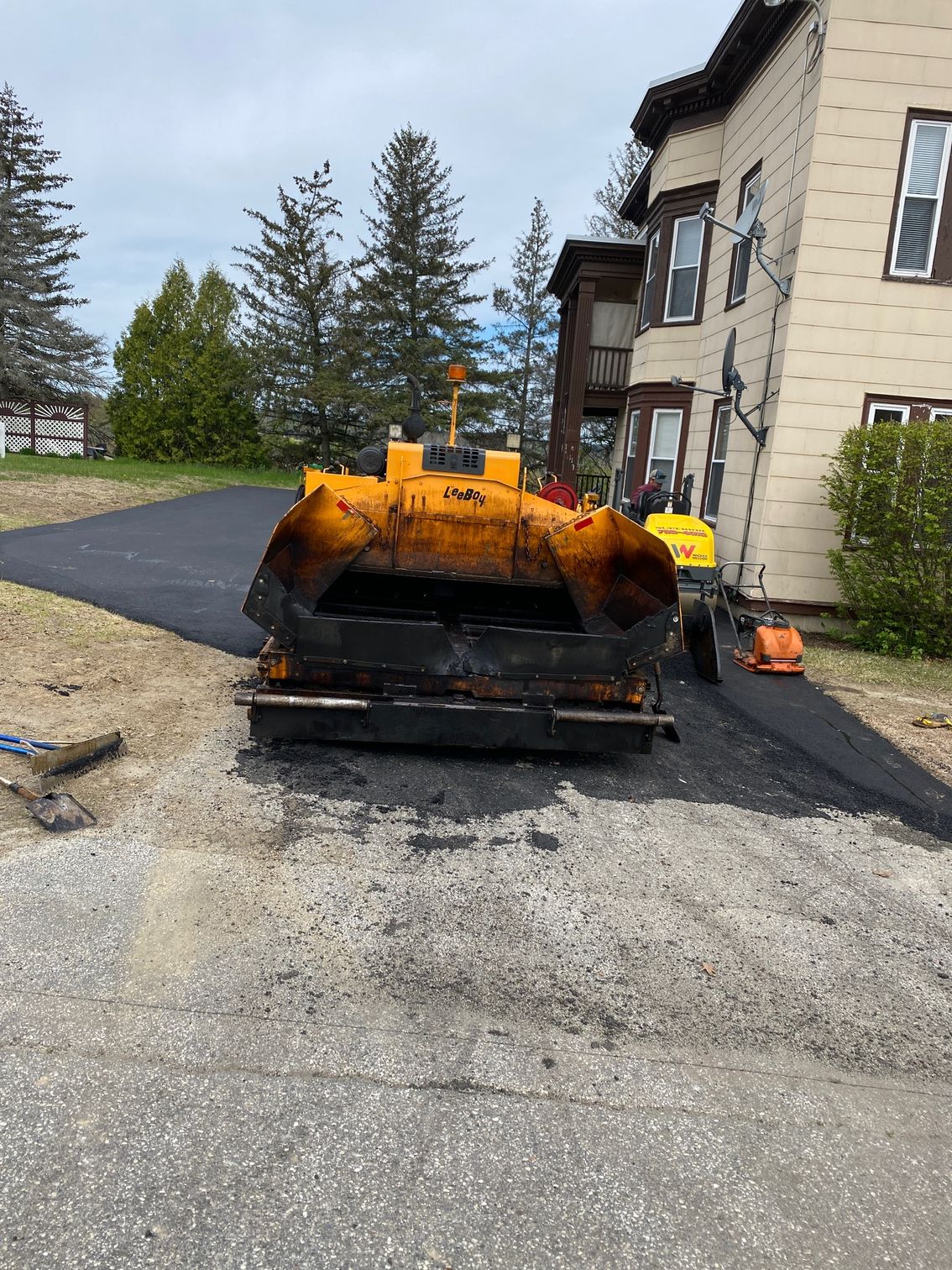 A yellow and black machine is sitting on the side of a road in front of a building