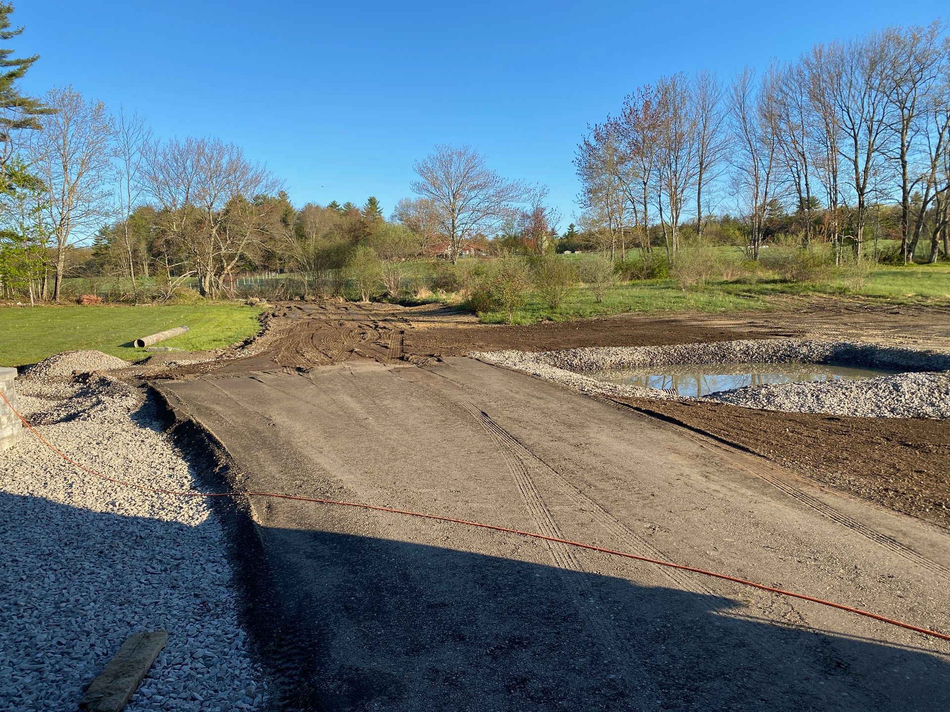 A dirt road going through a field with trees in the background