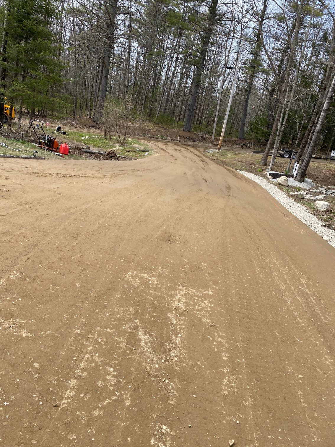 A dirt road going through a forest with trees on both sides