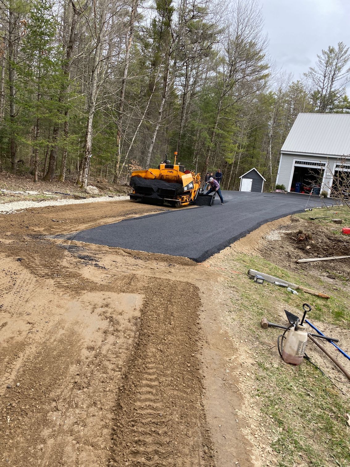 A machine is laying asphalt on a dirt road