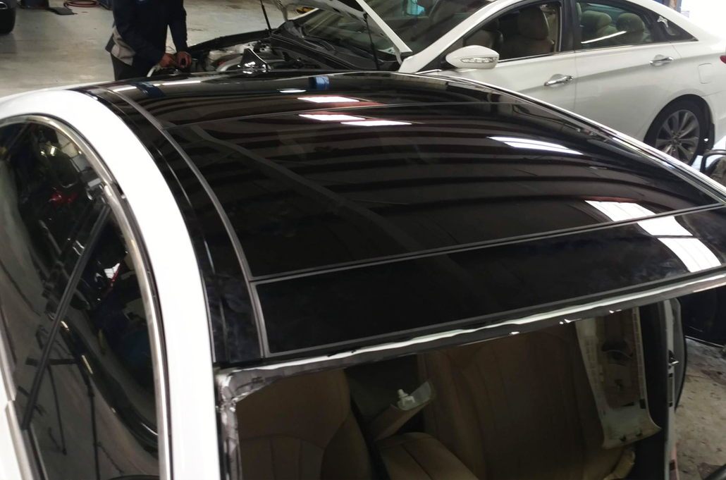 Black car roof with glossy sunroof panels inside an indoor showroom