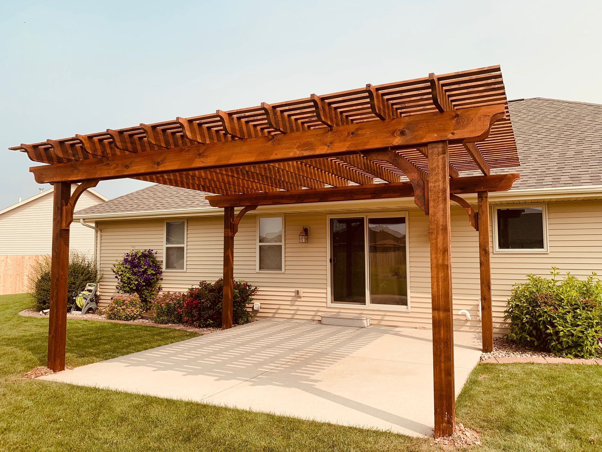A wooden pergola is sitting in front of a house.
