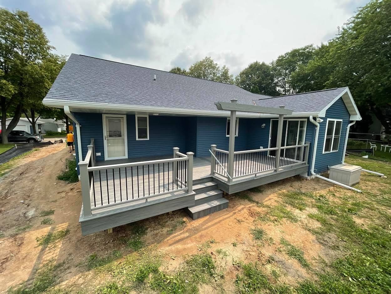 A blue house with a large porch and a gray roof.