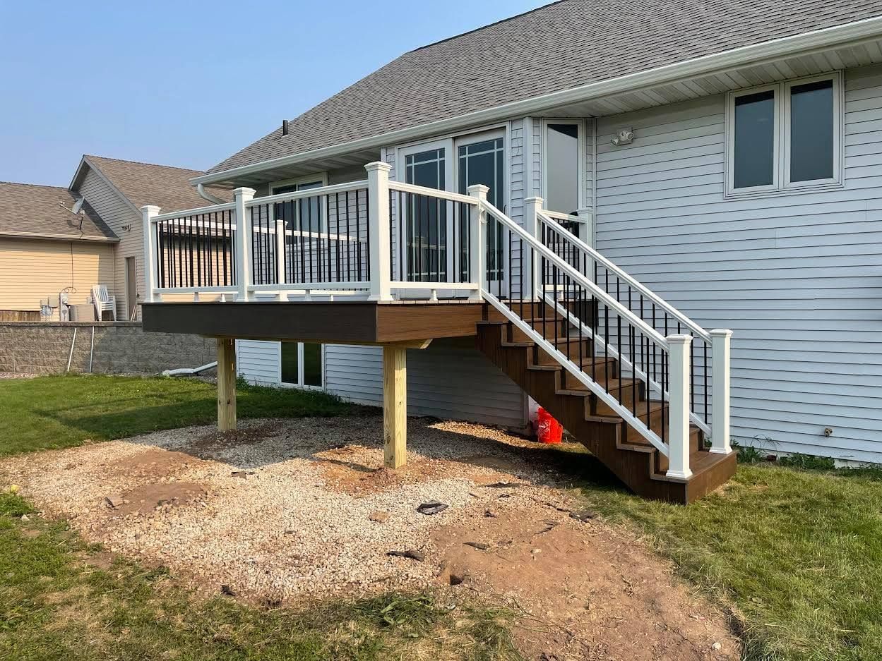 A deck with stairs leading up to it is in front of a house.