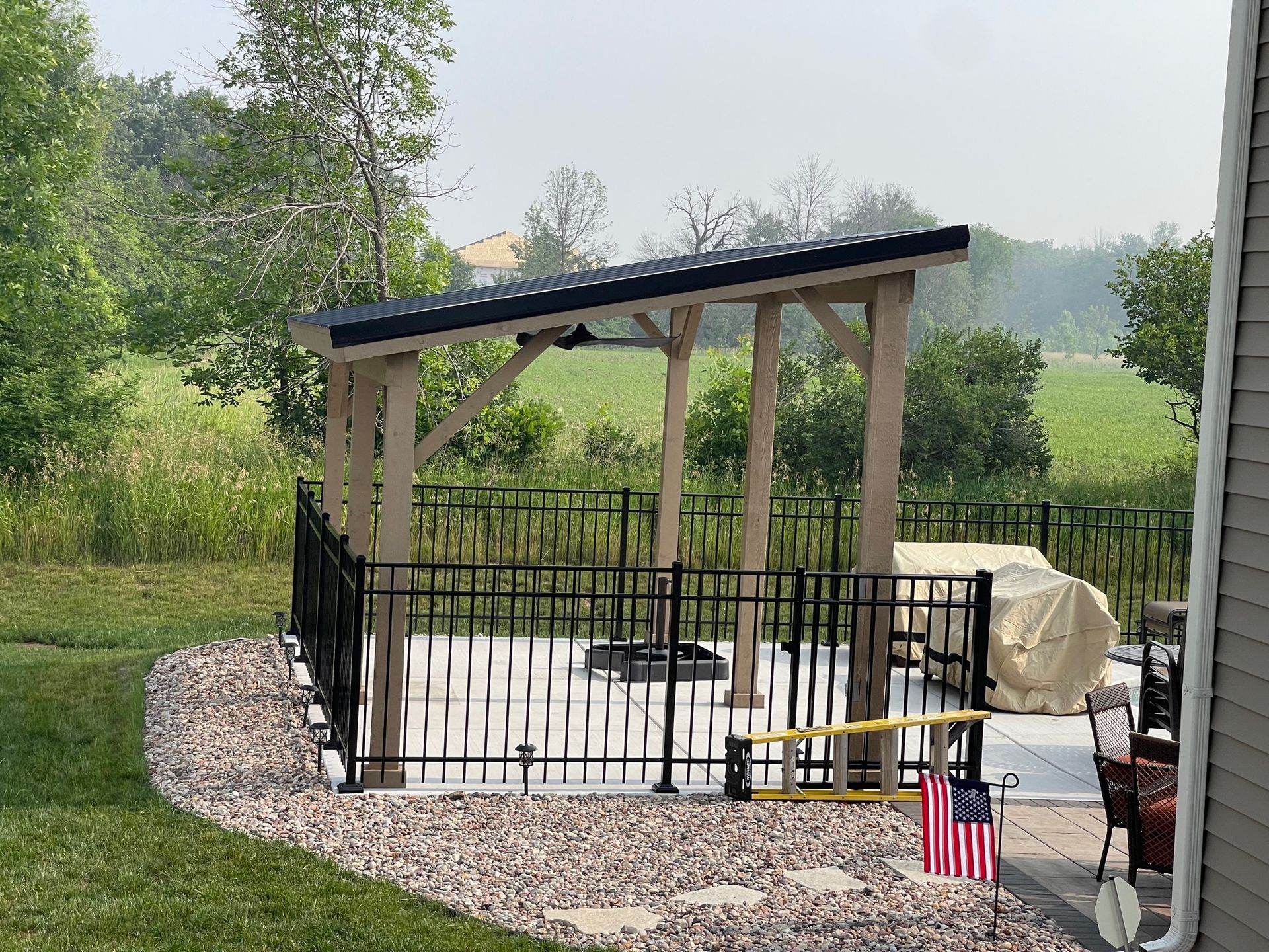 There is a gazebo in the backyard with a fence around it.